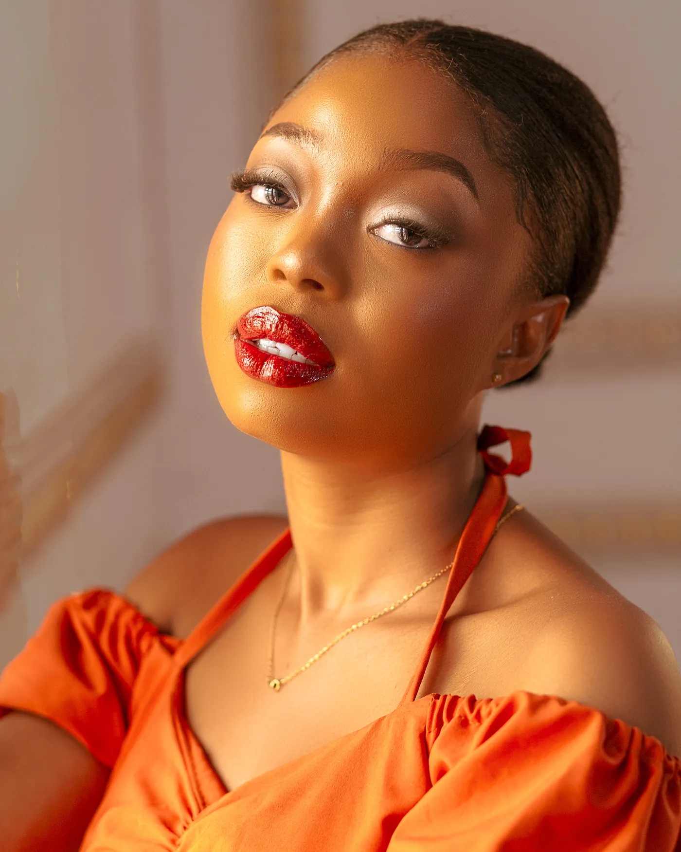 Close portrait of Angela in an orange off-shoulder top with a red lip